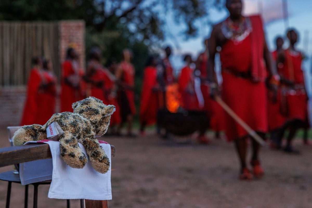 A young girl leaves her teddy to go and dance with Maasai