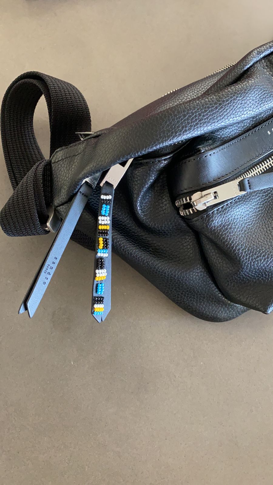 The leather zipper pull of a belt bag